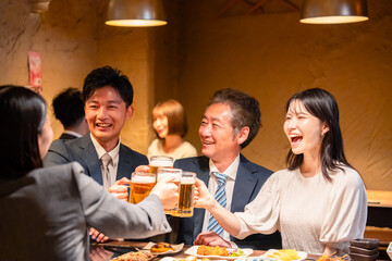 居酒屋で乾杯をする男女のビジネスパーソン