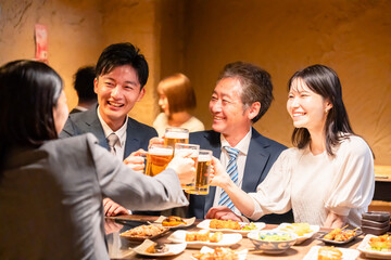 居酒屋で乾杯をする男女のビジネスパーソン