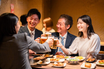 居酒屋で乾杯をする男女のビジネスパーソン