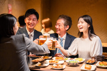 居酒屋で乾杯をする男女のビジネスパーソン