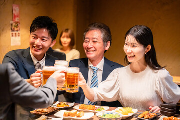 居酒屋で乾杯をする男女のビジネスパーソン