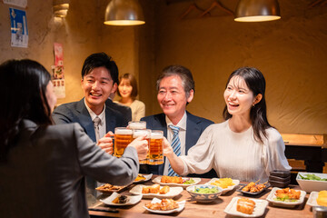 居酒屋で乾杯をする男女のビジネスパーソン