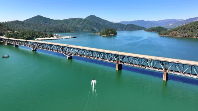 Shasta Lake - Aerial Follow of Boat Going Under Bridge with Full Lake