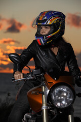 Obraz premium young woman with motorcycle at sunset