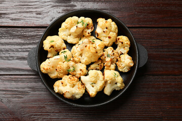 Tasty baked cauliflower in baking pan on wooden table, top view