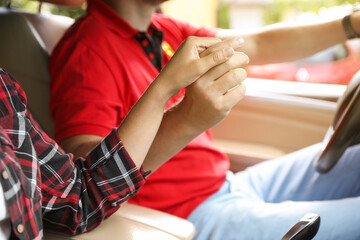 Obraz premium Lovely couple holding hands together while traveling by car, closeup
