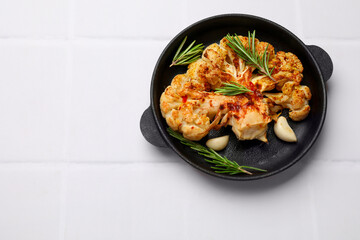 Delicious baked cauliflower steaks on white tiled table, top view. Space for text