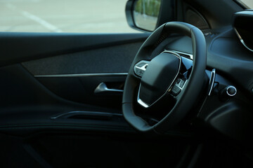 Steering wheel and dashboard inside of modern luxury car, closeup. Space for text