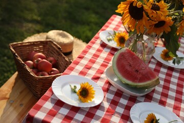 Plates with sunflowers and watermelon on table in garden