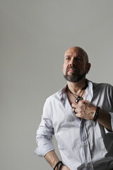 Portrait of bearded man with shaved head looking away and poses at the studio. Vertical.