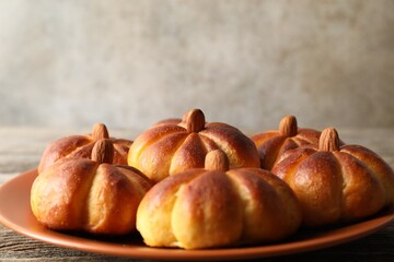 Tasty pumpkin shaped buns on wooden table, closeup