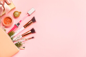 Different makeup brushes, decorative cosmetics and Christmas decor on pink background, flat lay. Space for text