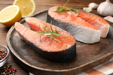 Fresh raw salmon steaks and spices on wooden table, closeup