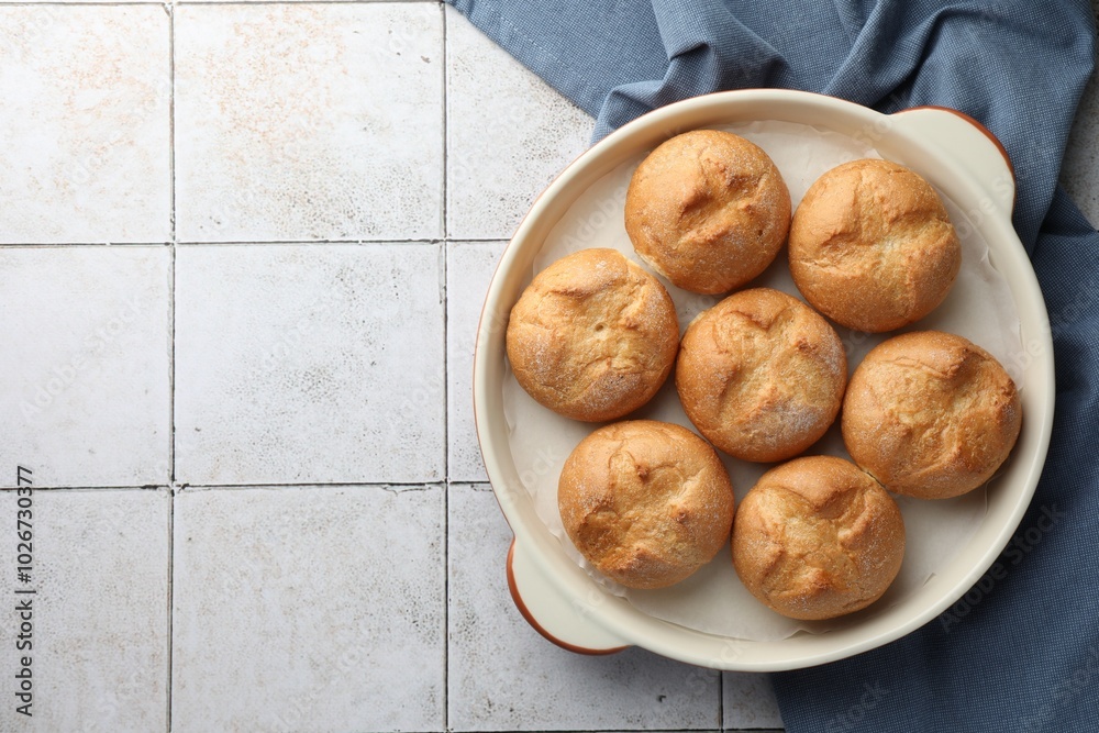 Canvas Prints Baking dish with homemade tasty buns on textured tiled table, top view. Space for text