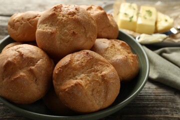 Homemade tasty buns in bowl on wooden table, closeup