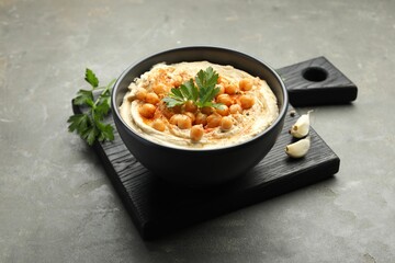 Delicious hummus with parsley, paprika and chickpeas on grey table