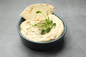Delicious hummus in bowl and pita on grey table, closeup