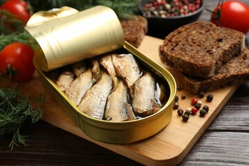 Tasty sprats in tin can served on wooden table, closeup
