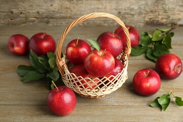Fresh ripe red apples in wicker basket on wooden table