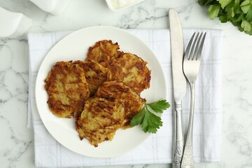 Delicious potato pancakes served on white marble table, flat lay