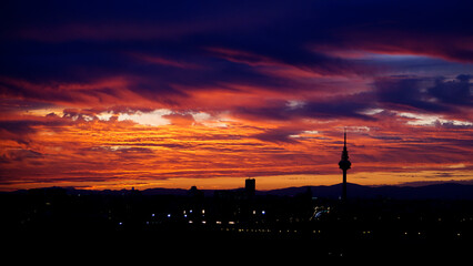 Fototapeta premium Panoramic view of the skyline of the city of Madrid at sunset with reddish tones and the profile of the piruli