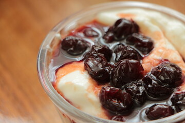 Close up the Yogurt in a glass bowl and cherry jam on top. Yoghurt dessert. Healthy sour-sweet dessert