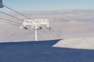 Ski lift covered with ice, cloud floating over the valley in the background from above, sunny, clear weather, winter, Slovakia, Chopok, telephoto