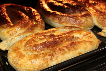 Borek also burek baked filled spinach pastries made of a thin flaky dough on the black baking tray in the oven. Turkish borek.
