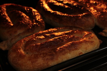 Borek also burek baked filled spinach pastries made of a thin flaky dough on the black baking tray in the oven. Turkish borek.