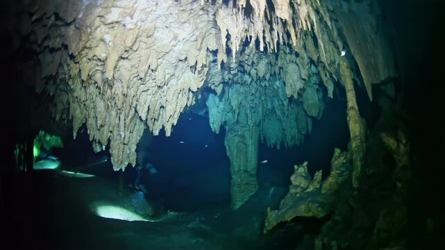 A cave with a blue light shining on it. The cave is full of stalactites and stalagmites