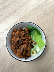 A bowl of braised pork with bok choy.