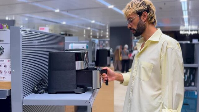 Man inspecting air fryer in an electronics store.