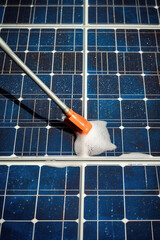 Close-up manual cleaning of solar modules with water. Worker cleaning solar panels after installation. Servicing and maintenance of solar panels