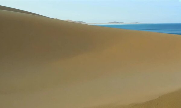 Pan shot with sand dunes: The camera starts by focusing on the texture of sand dunes, then pans across the dunes to show the transition to the beach and ocean.