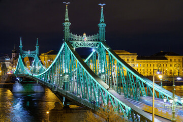 Obraz premium Freedom Bridge at night, illuminated, from above, with the Danube river, houses in the background, Budapest, telephoto