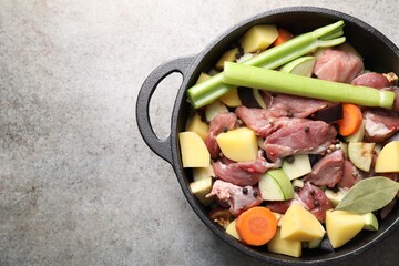 Cooking stew. Uncooked meat and vegetables in pot on light grey table, top view. Space for text