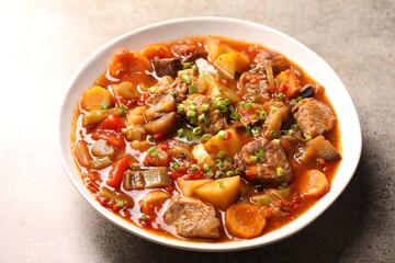Delicious stew with vegetables in bowl on light grey table, closeup