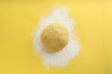 Cooking homemade pie. Raw dough and flour on yellow background, top view
