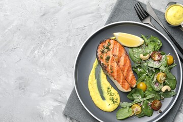 Tasty grilled salmon steak with sauce and salad on grey textured table, top view. Space for text