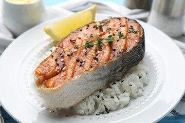 Tasty grilled salmon steak with rice, thyme, lemon and sesame seeds on table, closeup