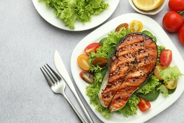 Tasty grilled salmon steak with vegetables served on light grey table, top view