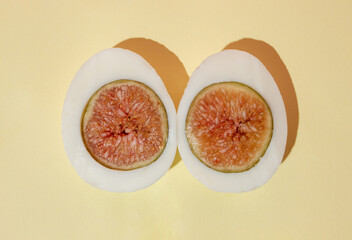 Two halves of a boiled egg made of egg whites and figs. Flat lay