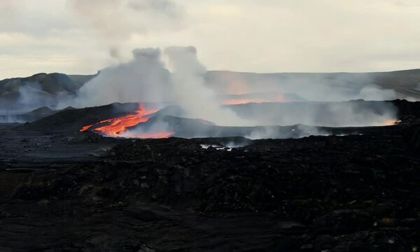 Tracking shot with fiery geysers: The camera starts with a close-up of fiery geysers shooting from the volcano. It then tracks forward to capture the eruption&rsquo;s full-scale and surrounding volcanic fea
