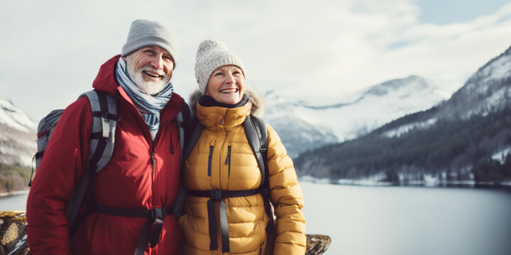 Senior couple 60 years old hiking among snowy mountains near a lake, Retiree travel and activities concept
