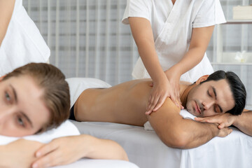 Caucasian couple customer enjoying relaxing anti-stress spa massage and pampering with beauty skin recreation leisure in day light ambient salon spa at luxury resort or hotel. Quiescent