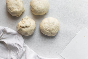 Overhead view of challah dough divided into balls on a white granite countertop, top view of homemade challah dough balls on white countertop, process of making challah