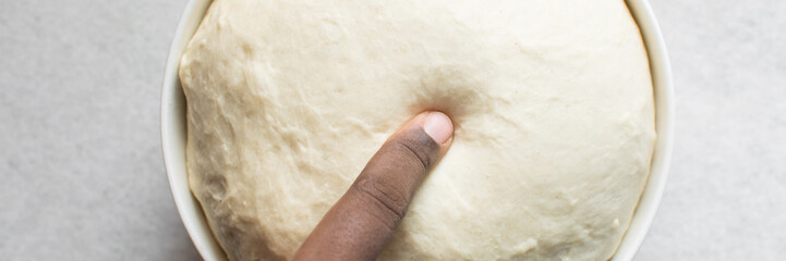 Overhead view of proofed bread dough, Checking if dough is proofed using a finger poke test, process of making bread