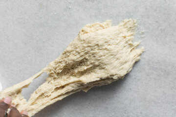 overhead view of dough being stretched to check if has been kneaded enough, bread dough being stretched to check for gluten development