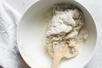 Overhead view of challah dough on a white countertop, top view of homemade challah dough being mixed on white granite countertop, process of making challah