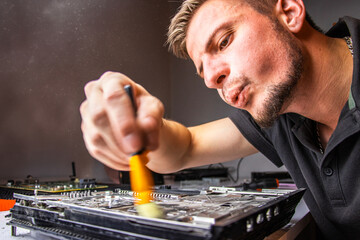 A man works intently on a board, using a brush to clean it. He carefully inspects the parts while...